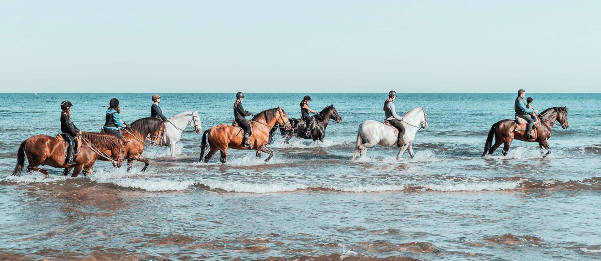 Centro Hípico Oliva Nova personas a caballo en el mar